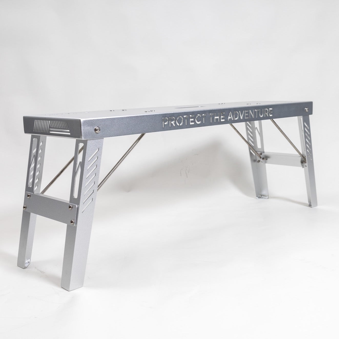 A lightweight portable bench made of aluminum with 'PROTECT THE ADVENTURE' text on the top, designed for multi-purpose use.