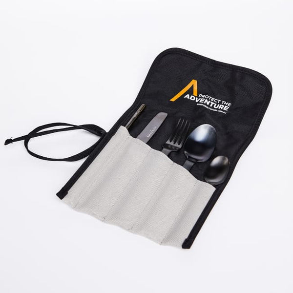 A set of black cutlery including a knife, fork, and spoons, within travel sleeve displayed in front of a white background.