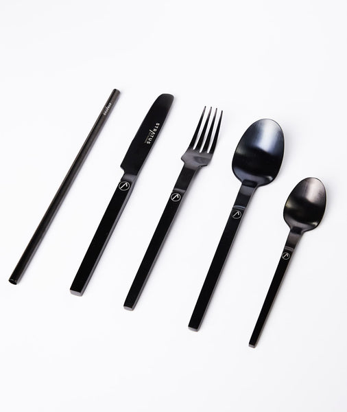 A set of black cutlery including a knife, fork, and spoons, displayed in front of a white background.
